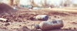 © Bonsales - Plastic bottles and other trash littering dry, dirty ground. This scene illustrates the widespread issue of environmental contamination and waste