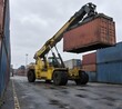 © Sekai - Reach stacker lifting shipping container in yard lane with extended boom