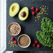 © Lintang91 - Fresh healthy ingredients including avocado kale quinoa and raspberries on a dark slate background.