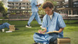 © DC Studio - Young medical student reads an open book and takes notes with academic materials and a laptop on a sunny campus, studying alone for medical school during a solo study session outdoors.