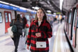 © JackF - Girl standing at metro stop, subway station platform, waiting for transport. She carefully reads signs and looks for required metro train departure platform.