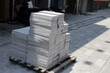 © Bowonpat - Stacked granite paving slabs bound with straps on street sidewalk.
