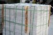 © Bowonpat - Stacked granite paving slabs bound with straps on street sidewalk.