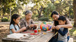 © Matos - Multi-generational Asian family enjoys crafting colorful lanterns together outdoors at a picnic table in a park setting