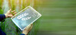 © wasan - Person holding a digital tablet with smart farming data interface in a green field. Concept of precision agriculture, agricultural technology, crop monitoring, and sustainable farm management.