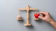 © Dedi Alfian studio - Person placing a red heart on a wooden scale to balance with a brain model, representing the conceptual choice between logic and emotion or heart and mind in decision making processes.
