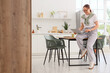 © Pixel-Shot - Remote work and work-life balance, young woman using a laptop in a modern home kitchen for freelance career and digital nomad lifestyle