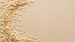 © Dzunstock - Rolled oats scattered on a beige surface, forming a curved pattern with empty space in the center.