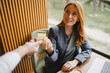© Novak - Businesswoman handing credit card for payment at cafe table