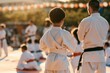 © Antony - Karate practice takes place outdoors with children in white uniforms during an event in the evening light