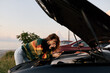 © SHOTPRIME STUDIO - Curious woman leans over a car engine on a roadside at sunset, inspecting components under the hood. Outdoor scene conveys repair work, problem solving, and calm focus in warm light.