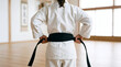 © Martin - Rear View of Child in White Uniform Tightening Black Belt in Martial Arts Dojo