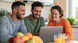 © AZ Studio - Three diverse friends laughing while looking at a laptop screen together in a bright home kitchen