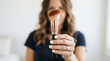 © kinkin - Close-up of a woman's hand presenting a professional cosmetic brush with soft bristles and an elegant design, ideal for flawless beauty application and daily makeup routines
