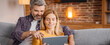 © Prostock-studio - Happy Caucasian Couple, Middle Aged, Smiling, Spending Quality Time Together While Using Tablet In Cozy Living Room Setting. Enjoying Relaxed Atmosphere, Sharing Content, Technology Concept.