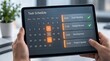 © SATEAYAM - Close-up of human hands holding a modern tablet displaying a digital task schedule and calendar interface for business planning, featuring project updates and meeting reminders in a workspace.