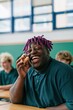 © Iryna - Laughing student with purple dreadlocks holding a sandwich in a classroom for lifestyle banner and background, cheerful candid portrait of youth