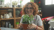 © Krakenimages.com - Woman holding a potted plant with hands cupping the pot in a flower studio workshop, smiling and presenting the plant; nurture joy.