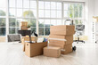 © Pixel-Shot - Corporate relocation and office move, cardboard boxes with business equipment in empty workspace during company downsizing or remote work transition