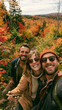 © Joyce - a man and two women, taking a selfie in a forest during autumn. The woman in the center wears a beige jacket, sunglasses, and a beanie.