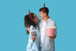 © Pixel-Shot - Date night and holiday entertainment, happy young couple with cinema tickets and popcorn wearing festive reindeer headbands on a blue background