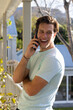 © Wavebreak Media - Man leaning against porch post with bracelet, holding smartphone to ear and laughing on porch