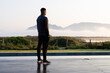 © Wavebreak Media - African American man standing on wet wooden deck beside pool in dark gear, facing misty mountains
