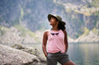 © CarlosBarquero - A Latina African American woman stands beside the lake and looks upward with her hands in her shorts pockets. Photographed in the Aiguestortes area of the Spanish Pyrenees.