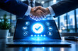 © Nazmun - Successful business deal sealed with a handshake over a laptop displaying quality assurance icons