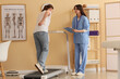 © Pixel-Shot - Physical therapy and rehabilitation, patient with back pain walking on treadmill during medical consultation with physiotherapist in clinic office