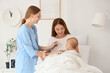 © Pixel-Shot - Pediatric healthcare and wellness, doctor examining baby with stethoscope during home visit with mother in bright bedroom for infant medical checkup