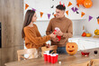 © Pixel-Shot - Halloween party celebration, young couple playing beer pong with red plastic cups in a decorated home kitchen for a festive holiday social gathering