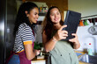 © Alvaro Lavin/Stocksy - Two women cooking and looking at a digital tablet in kitchen