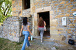 © Alvaro Lavin/Stocksy - Women friends entering stone house for rural vacation