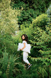 © ChaoShu Li/Stocksy - Chinese woman happily playing with a pillow in a garden