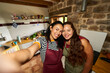 © Alvaro Lavin/Stocksy - Women smiling taking selfie in rustic kitchen