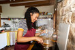 © Alvaro Lavin/Stocksy - Smiling woman cooking healthy meal in rustic kitchen