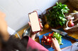 © Alvaro Lavin/Stocksy - Woman holding smartphone with blank screen cooking healthy food