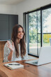 © Daniel - Woman welcomes a client with a wave during an online meeting on her laptop at home. Her friendly greeting supports client communication, remote work, business consultation and virtual service.