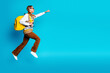 © deagreez - Young woman jumps with yellow backpack against bright blue background showcasing casual stylish fashion and upbeat energy