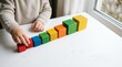 © SashaMagic - Child arranging colorful wooden blocks by increasing size on a white table to illustrate growth, learning, and development in a bright, clean educational setting