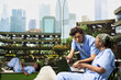 © DC Studio - Diverse medical students in blue scrubs use laptop notes to study together on a campus bench, collaborating outdoors as part of healthcare education.