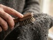 © Natalia - fabric fiber brushing macro Hand using a wooden brush to clean or de-pill a wool sweater.