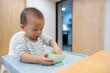 © leungchopan - Baby eating food from bowl in high chair