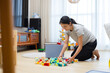 © leungchopan - Mother playing and organizing toys with child on floor