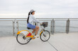 © leungchopan - Woman riding rental bicycle on coastal path