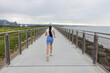 © leungchopan - Slim woman jogging alone on bridge pathway