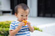 © leungchopan - Asian baby boy taking a bite of bread snack