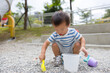 © leungchopan - Toddler boy squatting playing with sand and toys in park