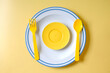 © amnarj2006 - Yellow spoon and fork on white plate over color background.